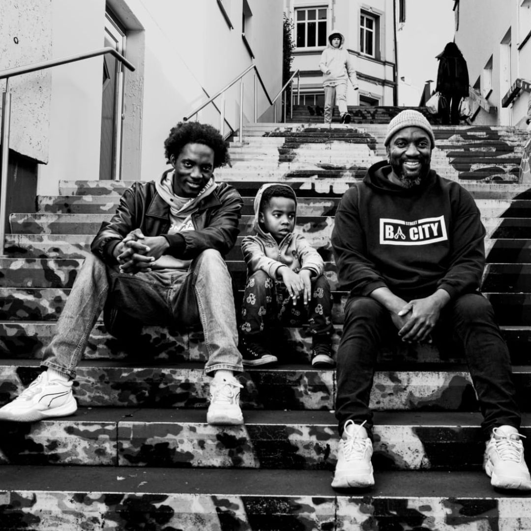 ein Schwarz-weiß-Foto von drei Personen, die auf einer Treppe sitzen 