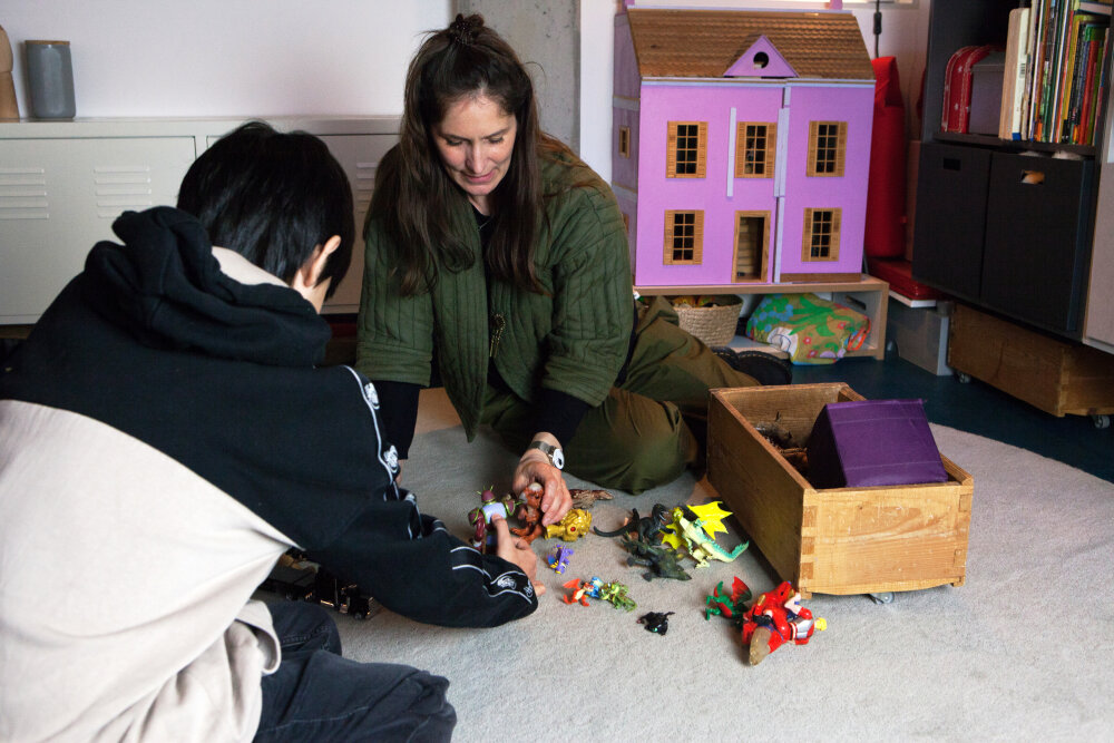 Das Bild zeigt die Therapeutin Kim mit einem Kind und Spielzeug